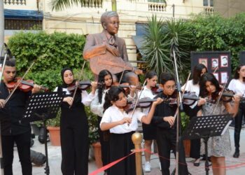 طلاب الكمان يعزفون أمام تمثال سيد درويش في دار الأوبرا بالإسكندرية